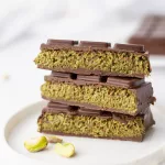 Recette de la fameuse tablette de chocolat Dubaï Chocolat Dubaï coupé et empilé sur une assiette blanche et quelques pistaches