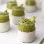 Verrine panna cotta lait de coco kiwi : le dessert de fêtes à préparer la veille Verrines de panna cotta au lait de coco surmontées d'une purée de kiwi, servies dans des pots en verre sur fond blanc